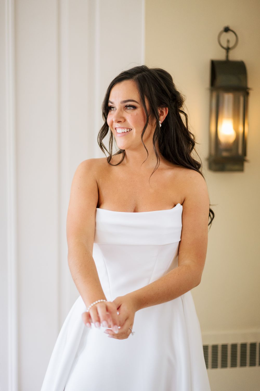 A joyful bride in a white strapless dress poses during a wedding photo session.