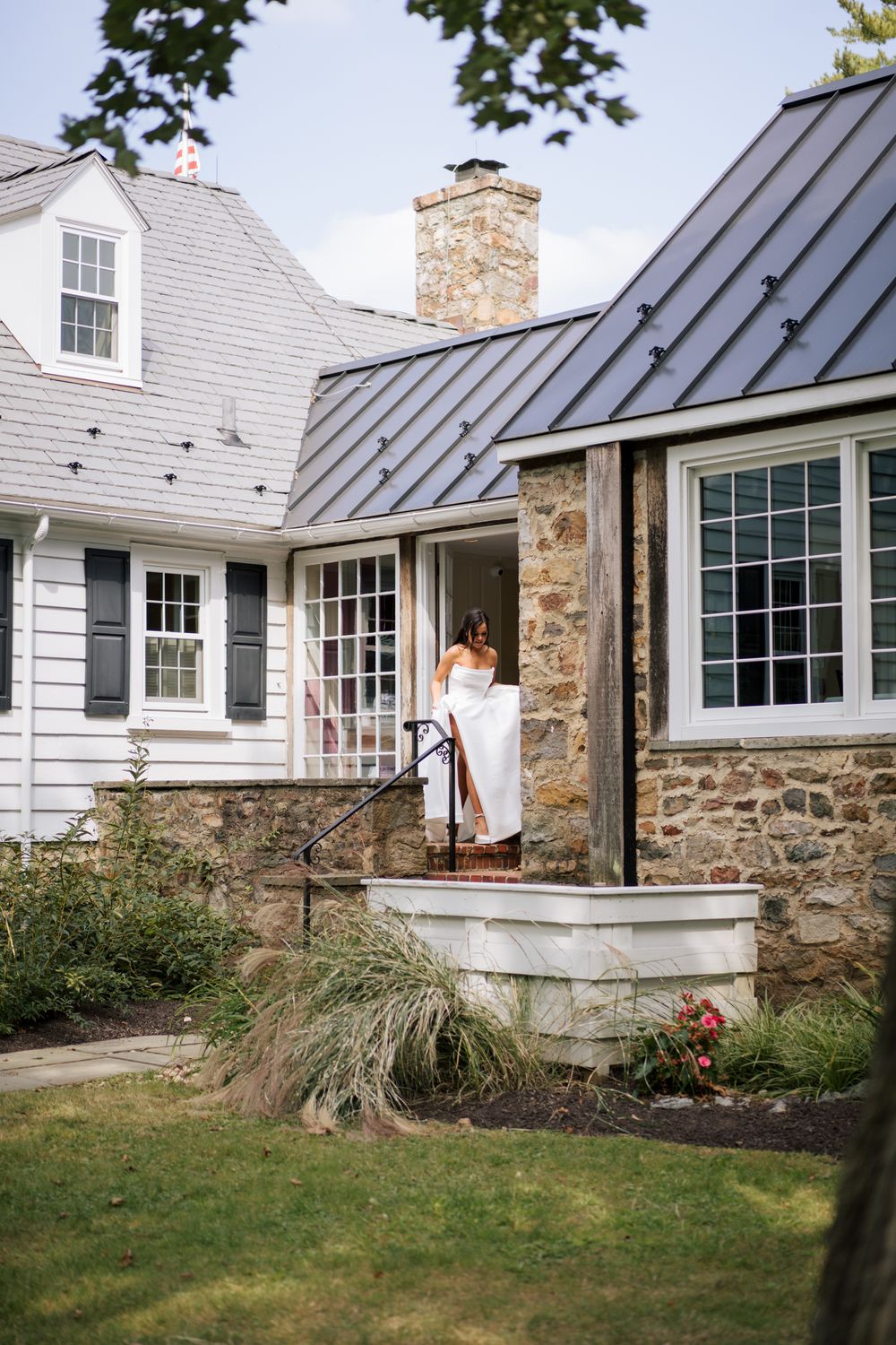 Modern farmhouse exterior with stone foundation, gray siding, and metal roof details.