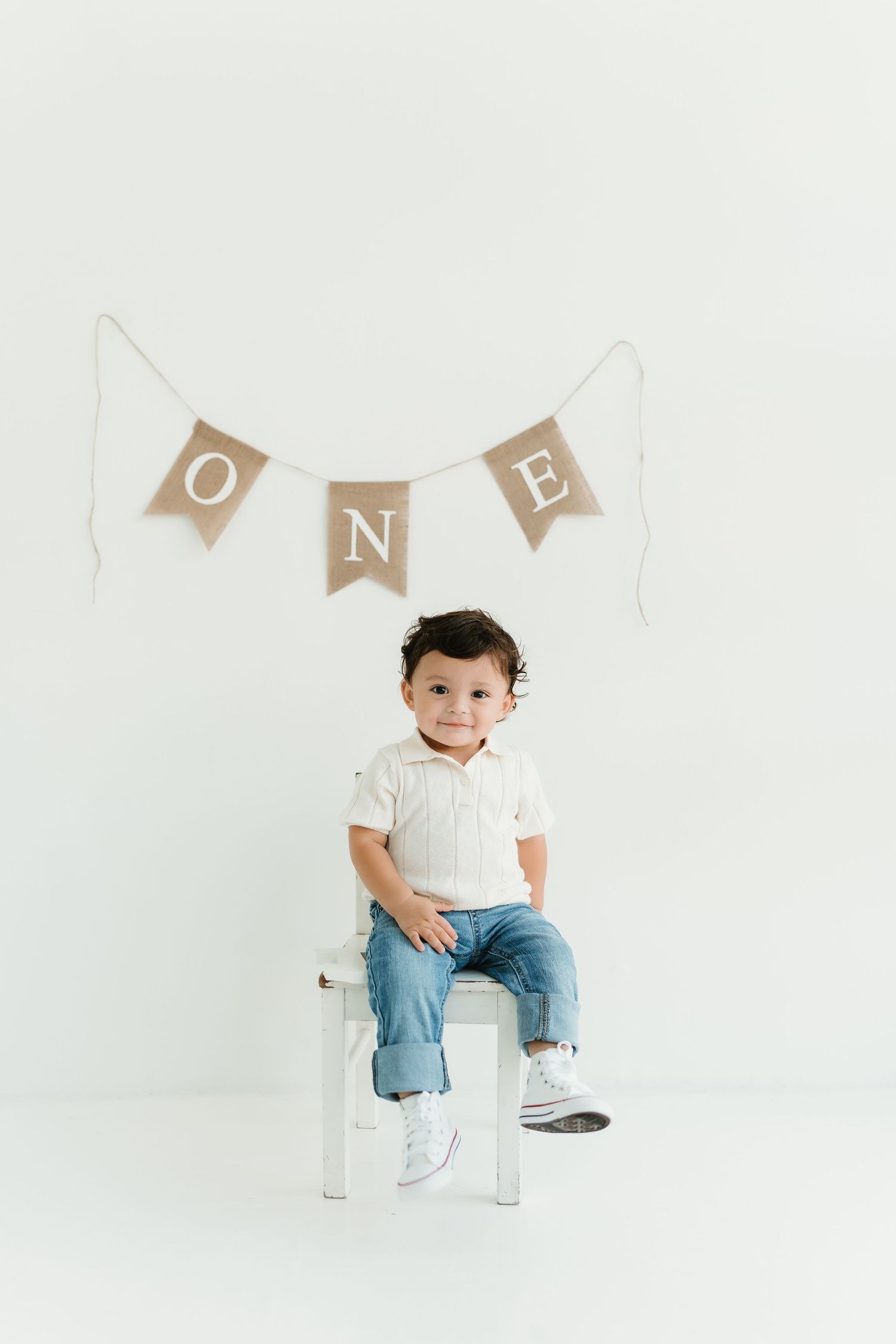 Simple white studio portrait setup with ONE banner and small chair.