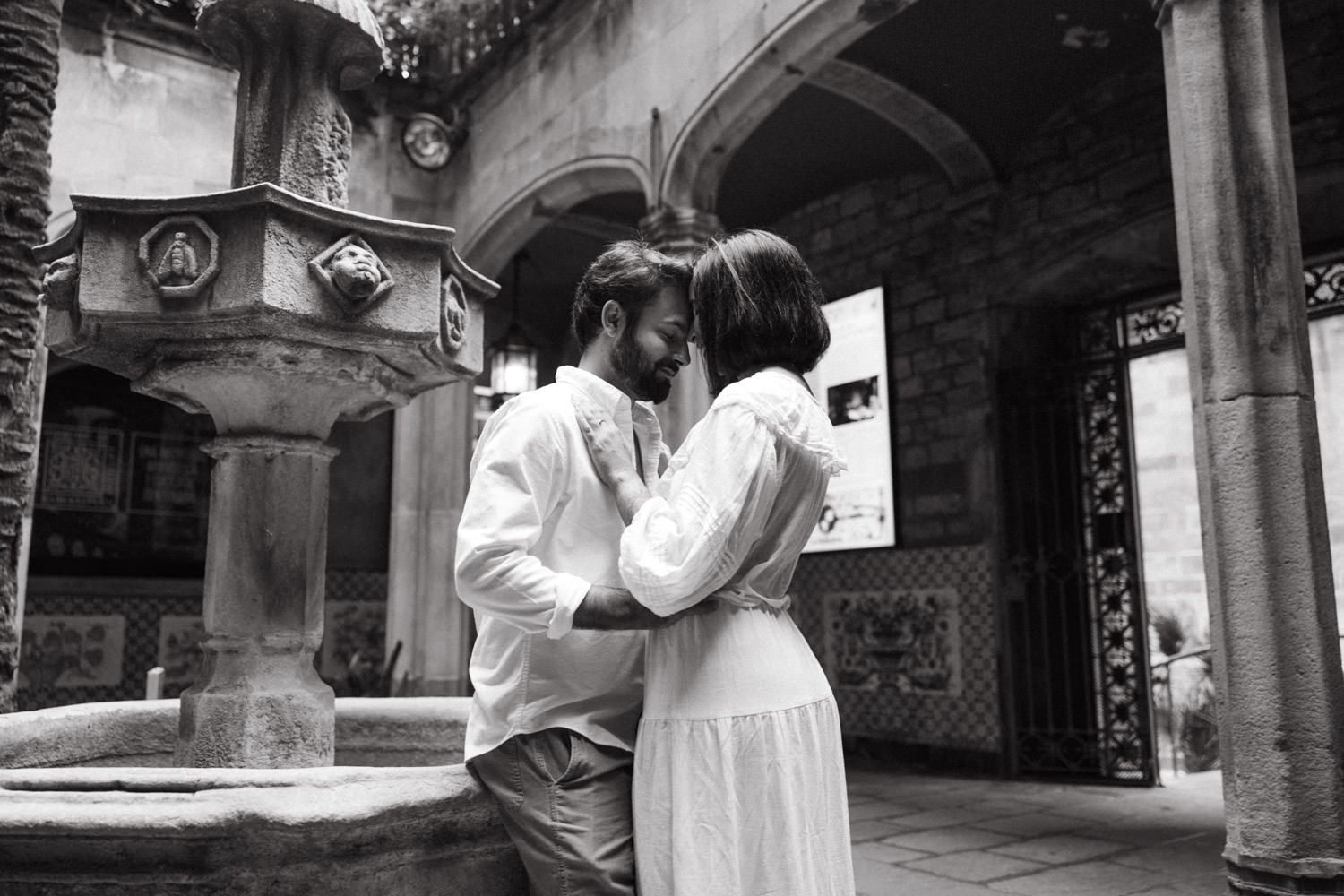 A couple shares tender moments in front of gothic architecture in black and white photos.