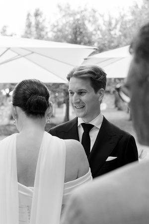 Black and white candid wedding moment captured under white tent canopy.
