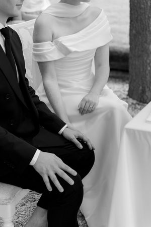 Black and white detail shot of bride's white off-shoulder wedding dress.