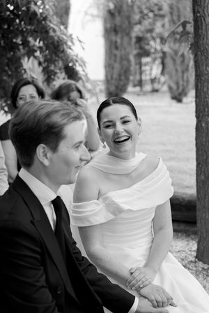 Black and white photo of a couple sharing a candid laughing moment at their wedding ceremony.