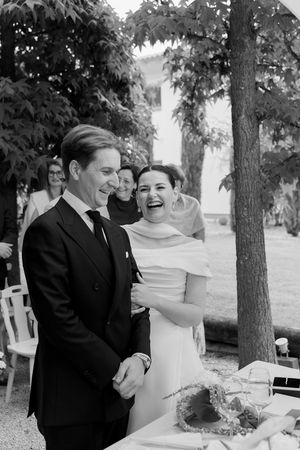 Black and white wedding photo showing a couple laughing together by a decorated table.