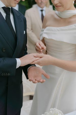 Close-up of hands during a wedding ring exchange ceremony outdoors.