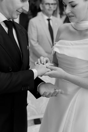 Black and white close-up of wedding couple exchanging rings during ceremony.