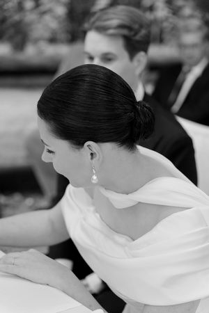 Close-up profile view of a bride in a white dress with elegant hair styling and pearl earrings.
