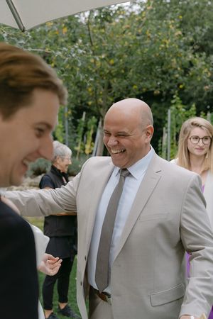 Candid moments of wedding guests laughing and embracing in a garden setting.
