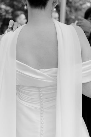 Close-up details of white wedding dress buttons and fabric along the back.