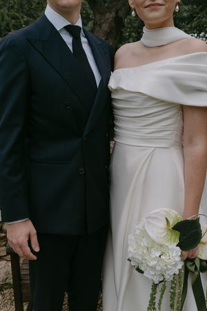 Elegant couple in formal wedding attire with bride holding white bouquet.