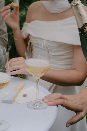 Hands holding wine glasses during an outdoor celebration with white tablecloths.