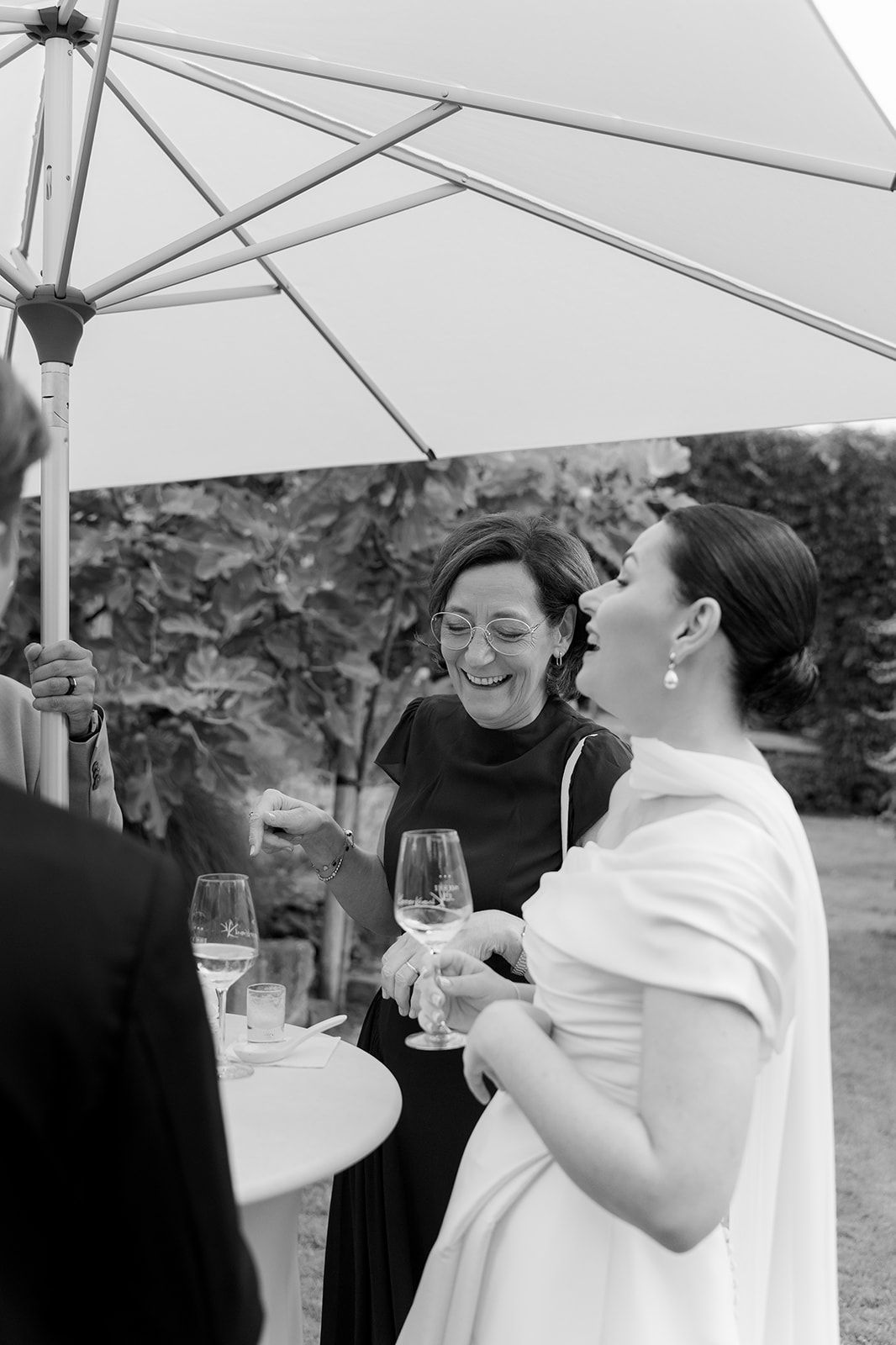 Black and white photo of guests enjoying a celebration under a white tent.