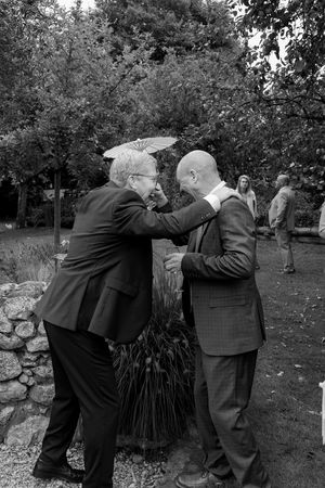 Black and white photo of guests embracing during an outdoor celebration.