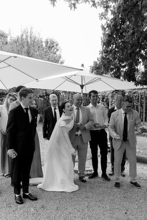 Wedding party and guests pose under white umbrellas during an outdoor celebration.