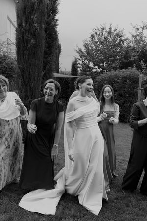Wedding guests and the bride share laughter during an outdoor celebration.
