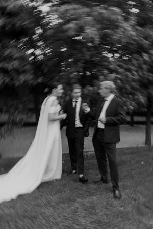 A blurred motion black and white photo captures wedding guests in conversation outdoors.