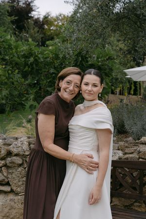 An emotional embrace between two wedding guests in a garden setting.