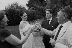 Wedding guests raise glasses for a toast during an outdoor celebration.