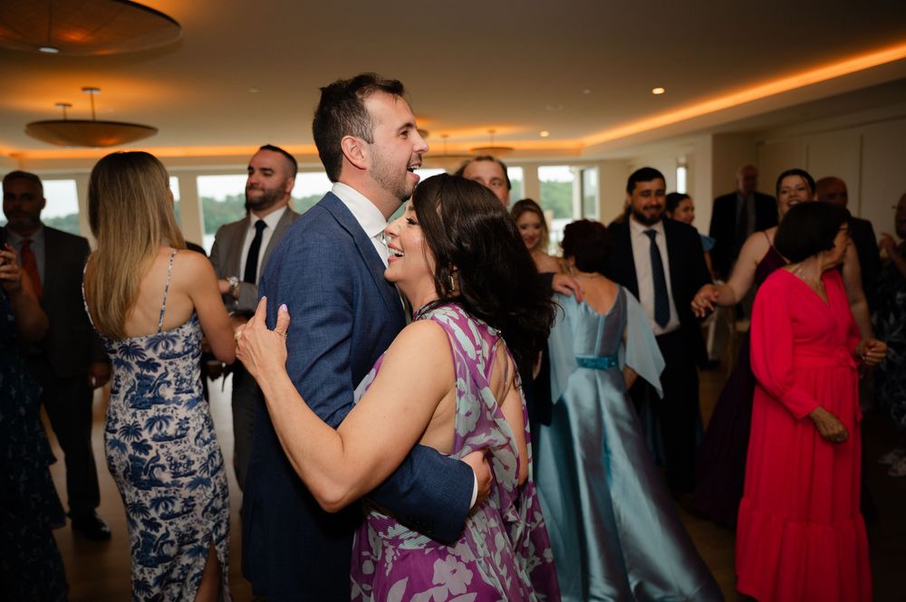 People dancing and celebrating at an indoor wedding reception with warm lighting and formal attire.