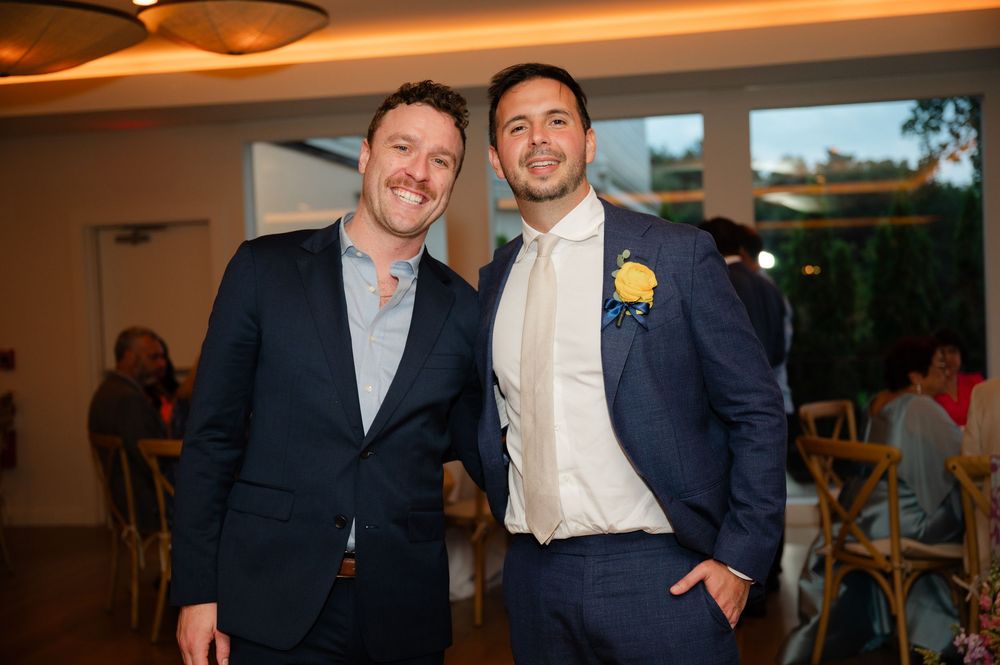 Two people in formal attire pose together for photos in a warmly lit indoor event space.