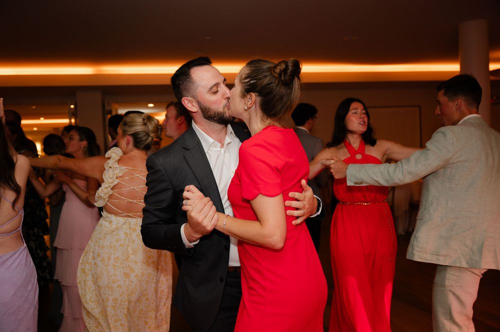 Couples dancing together at an indoor social event with warm lighting and formal attire.
