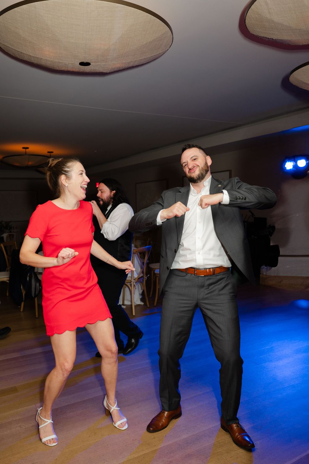 People dancing energetically on a dance floor with dramatic blue lighting at a festive event.