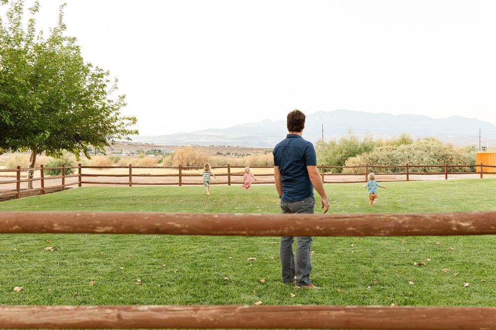 dad watching kids run around on grass family photos St. George utah