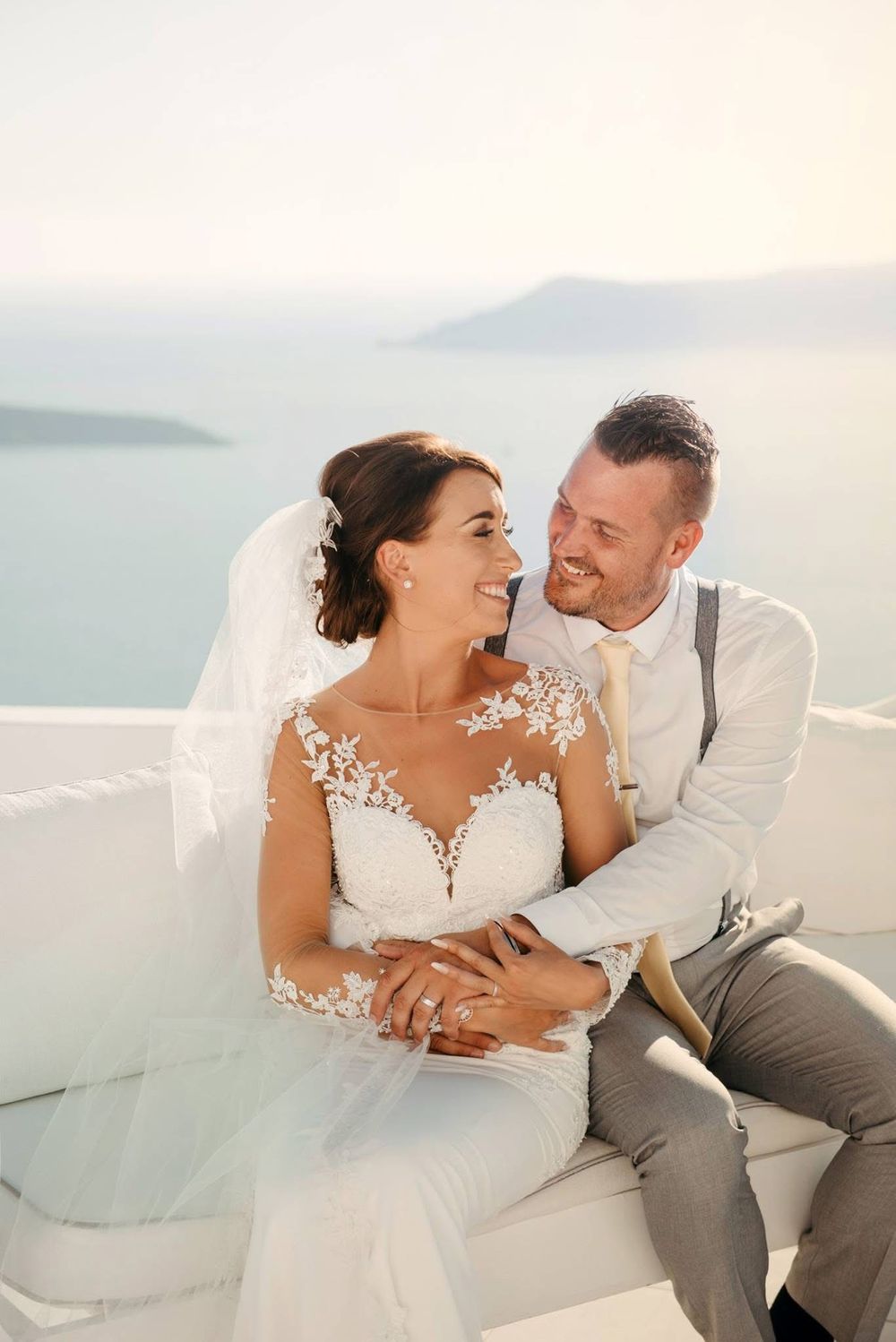 A couple shares intimate moments on a white couch overlooking a scenic coastal view.