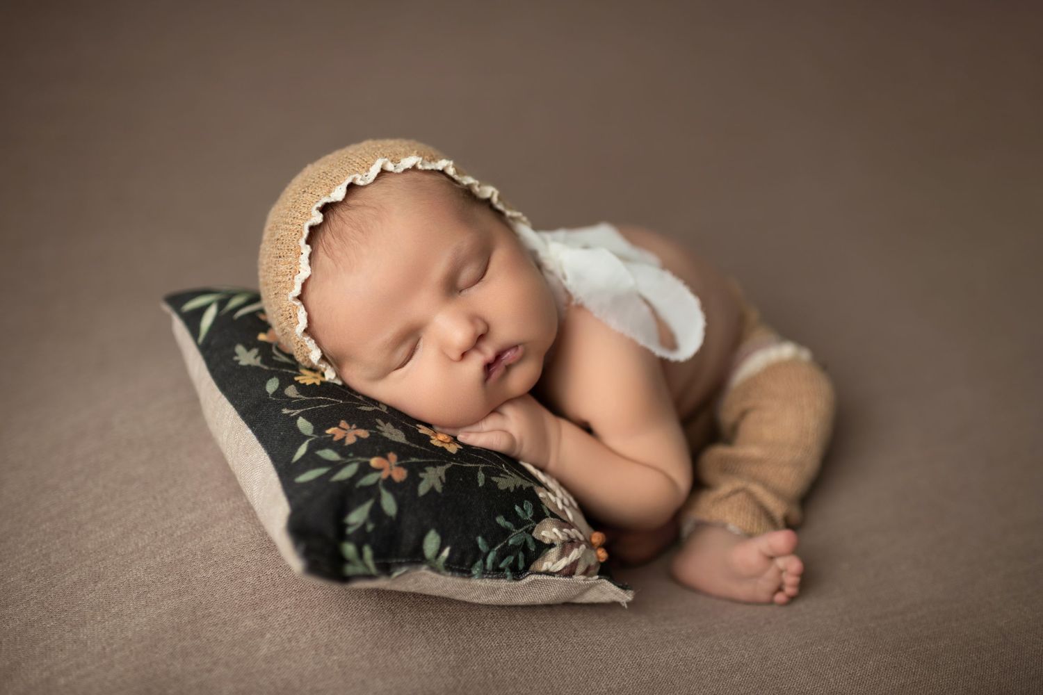 A series of tender newborn photography portraits showing an infant peacefully sleeping in neutral-toned settings.