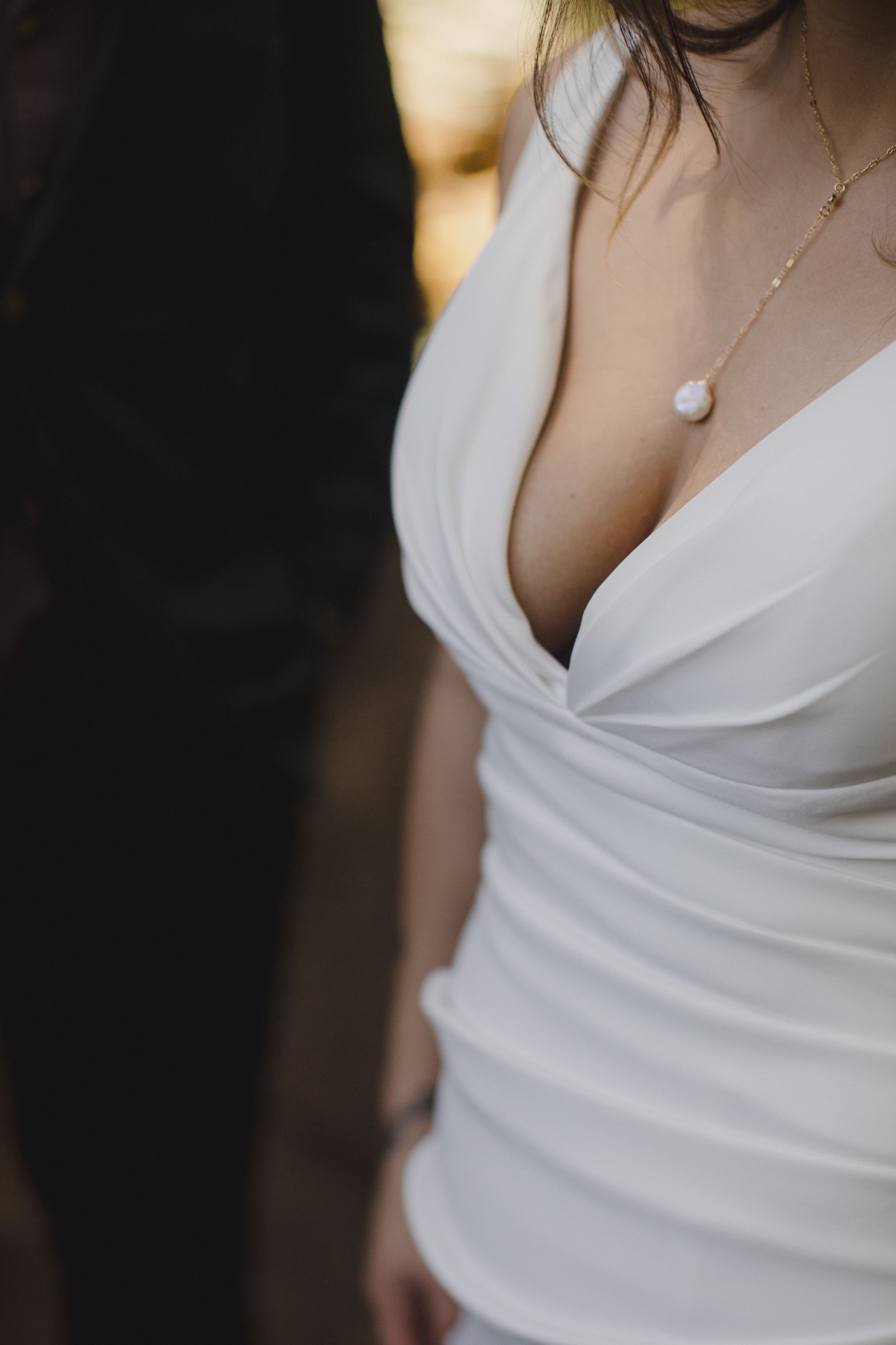 Close-up detail of an elegant white wedding dress neckline with a delicate pearl necklace on display.
