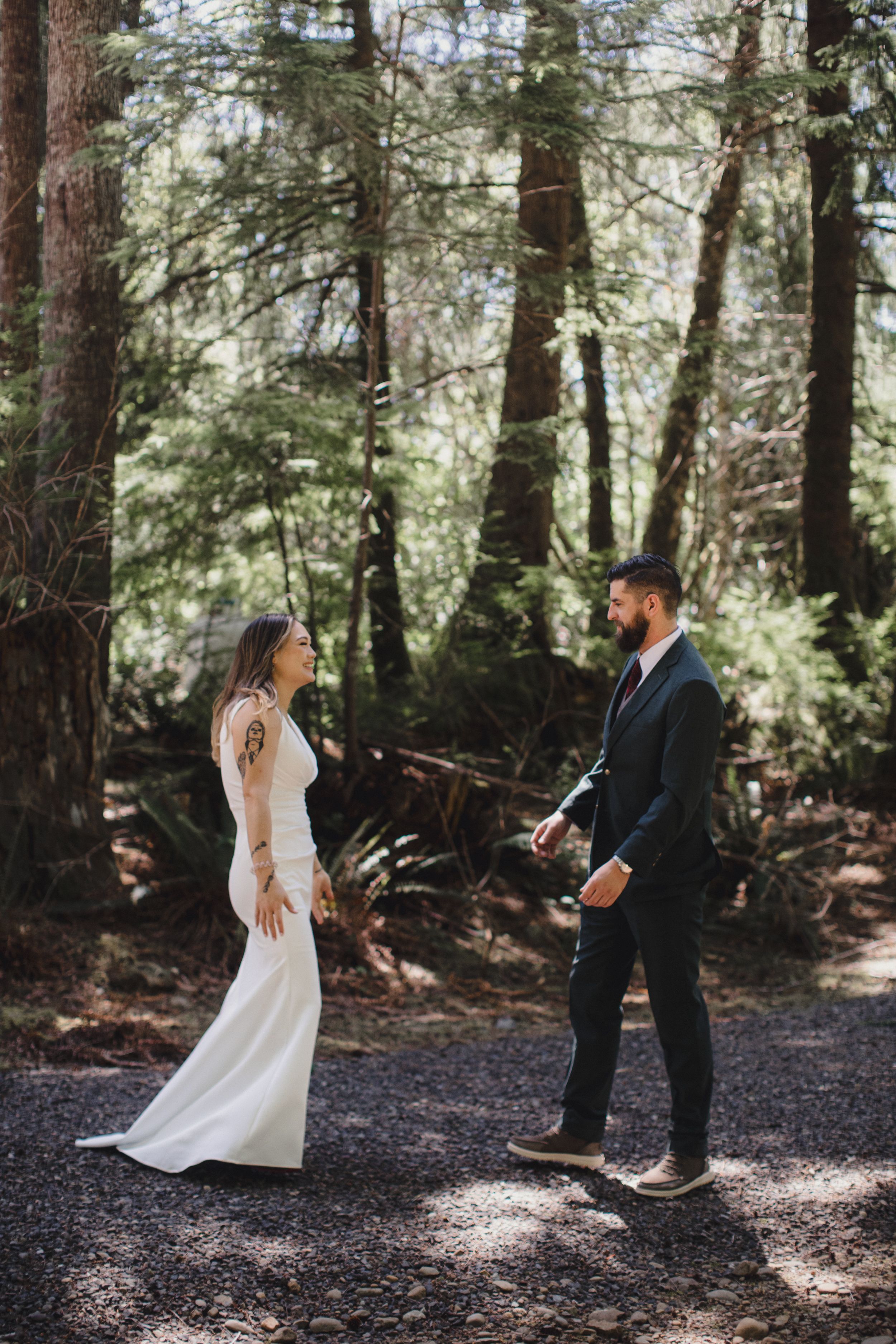 A couple having their first look moment in a sunlit forest during their intimate outdoor wedding.