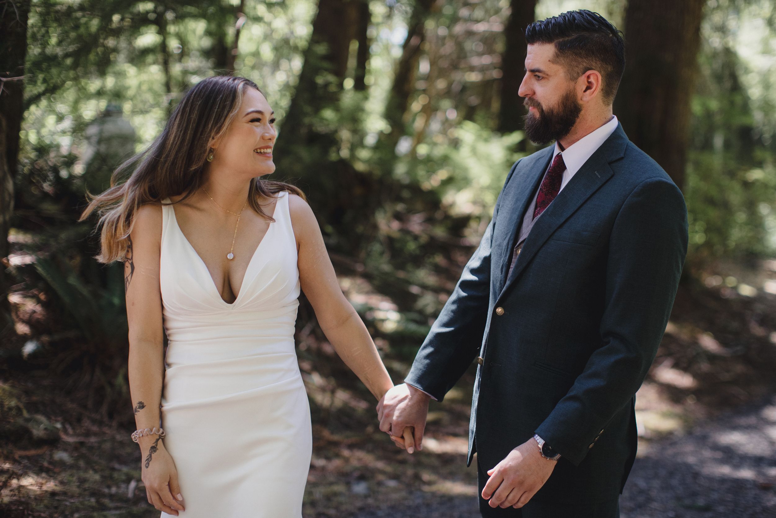 Couple shares intimate wedding moments in a romantic sunlit forest setting wearing formal attire.