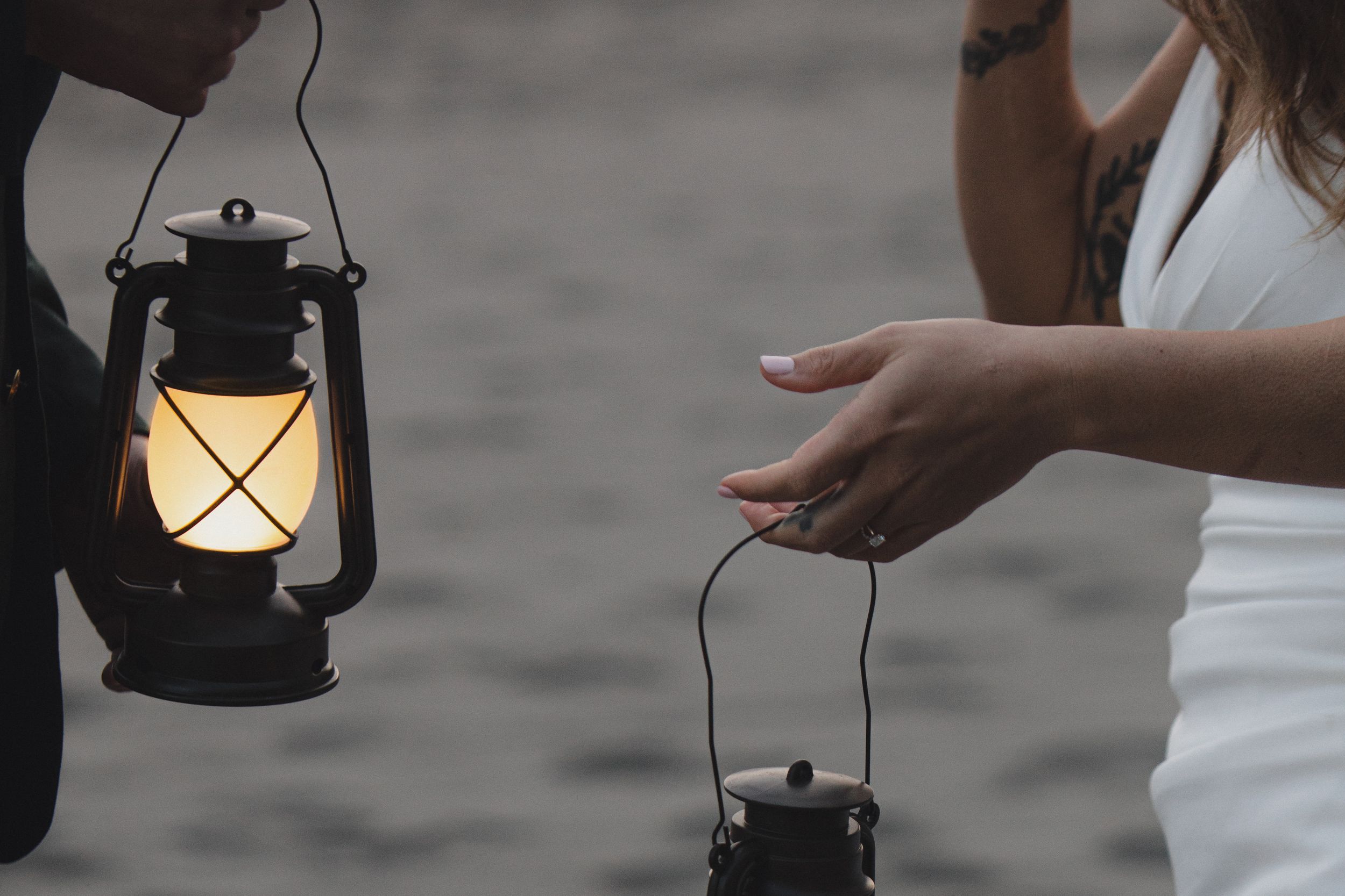 A set of vintage kerosene lanterns being held up against a dark background creates a moody atmospheric scene.