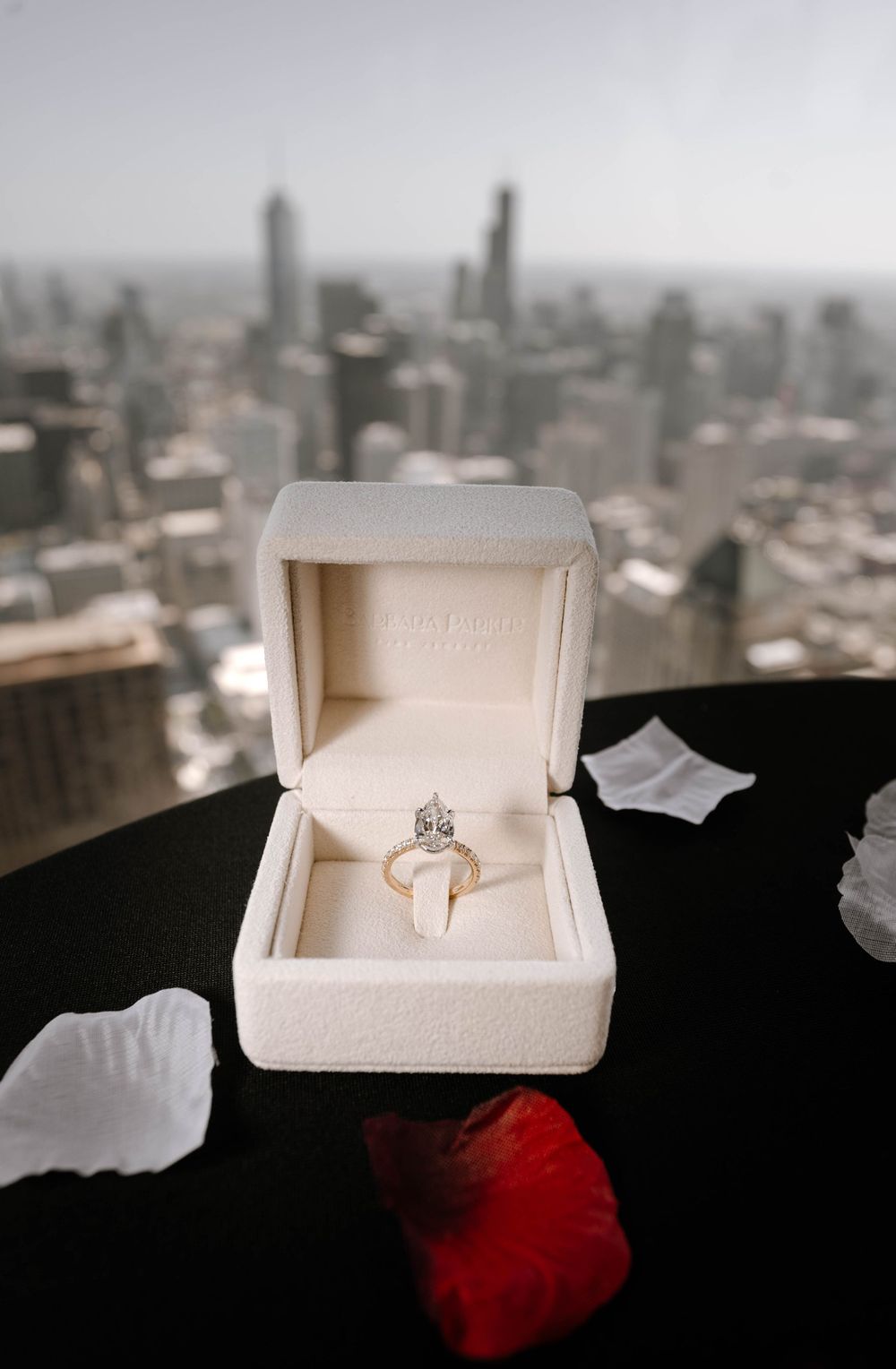 Close-up shots of an engagement ring in a white box with a cityscape backdrop.