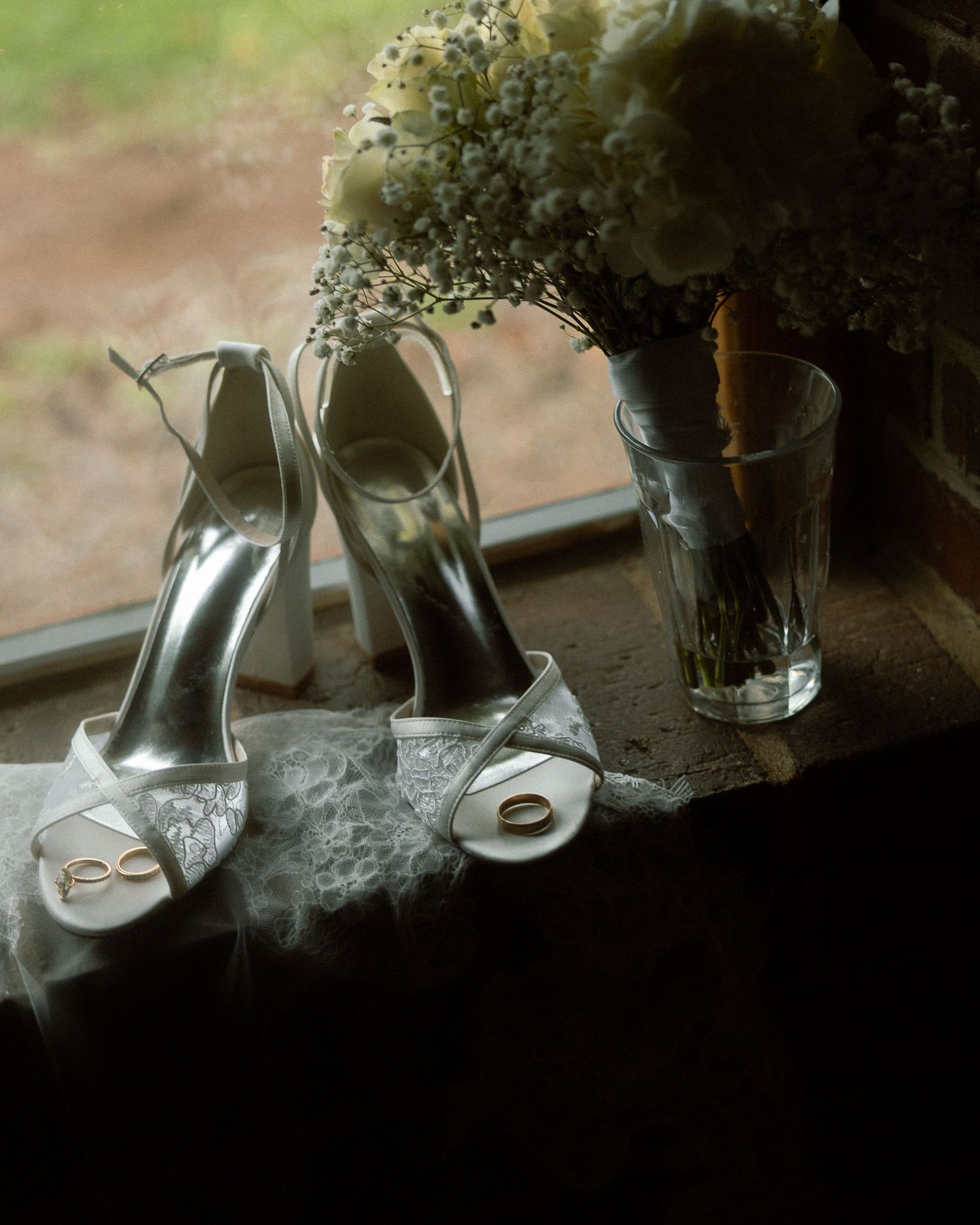Wedding accessories including bridal shoes and delicate floral arrangements in glass vases.
