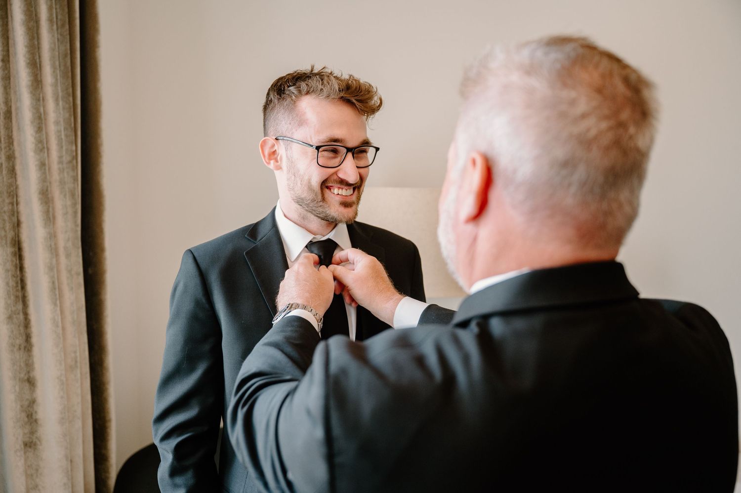 Groomsmen share an emotional moment hugging and crying during a wedding ceremony.