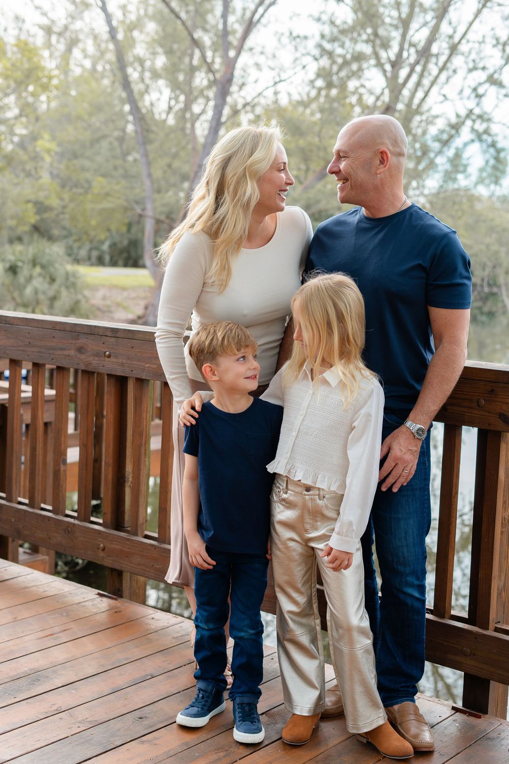 Family shares intimate moments on a wooden deck overlooking trees during an outdoor lifestyle photoshoot.