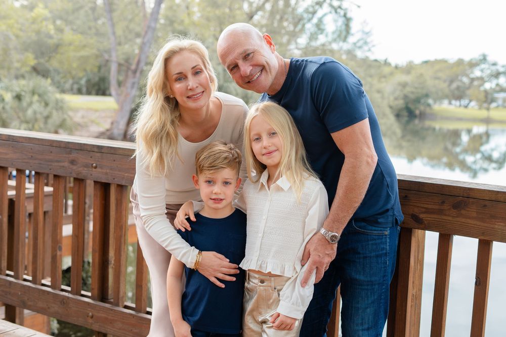 Family group poses together for outdoor photo series across multiple wooden deck settings in matching casual outfits.