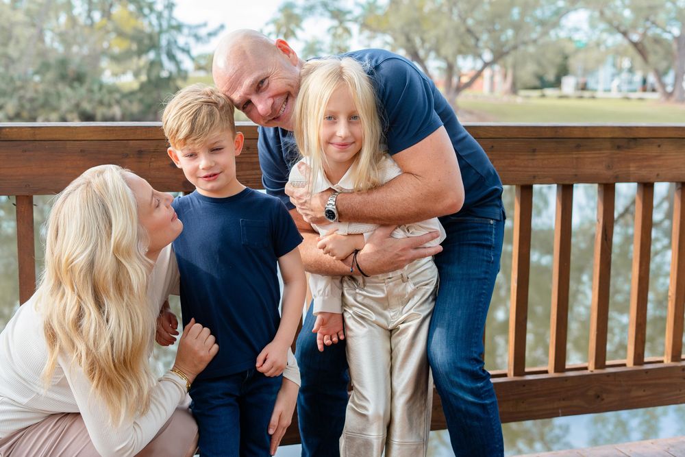Family enjoying tender moments together on a rustic wooden deck surrounded by natural greenery.