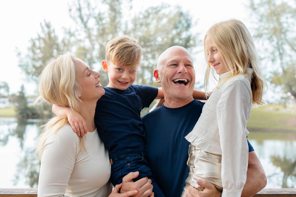 A row of candid family photo moments in neutral outfits standing together outdoors in a coastal setting.