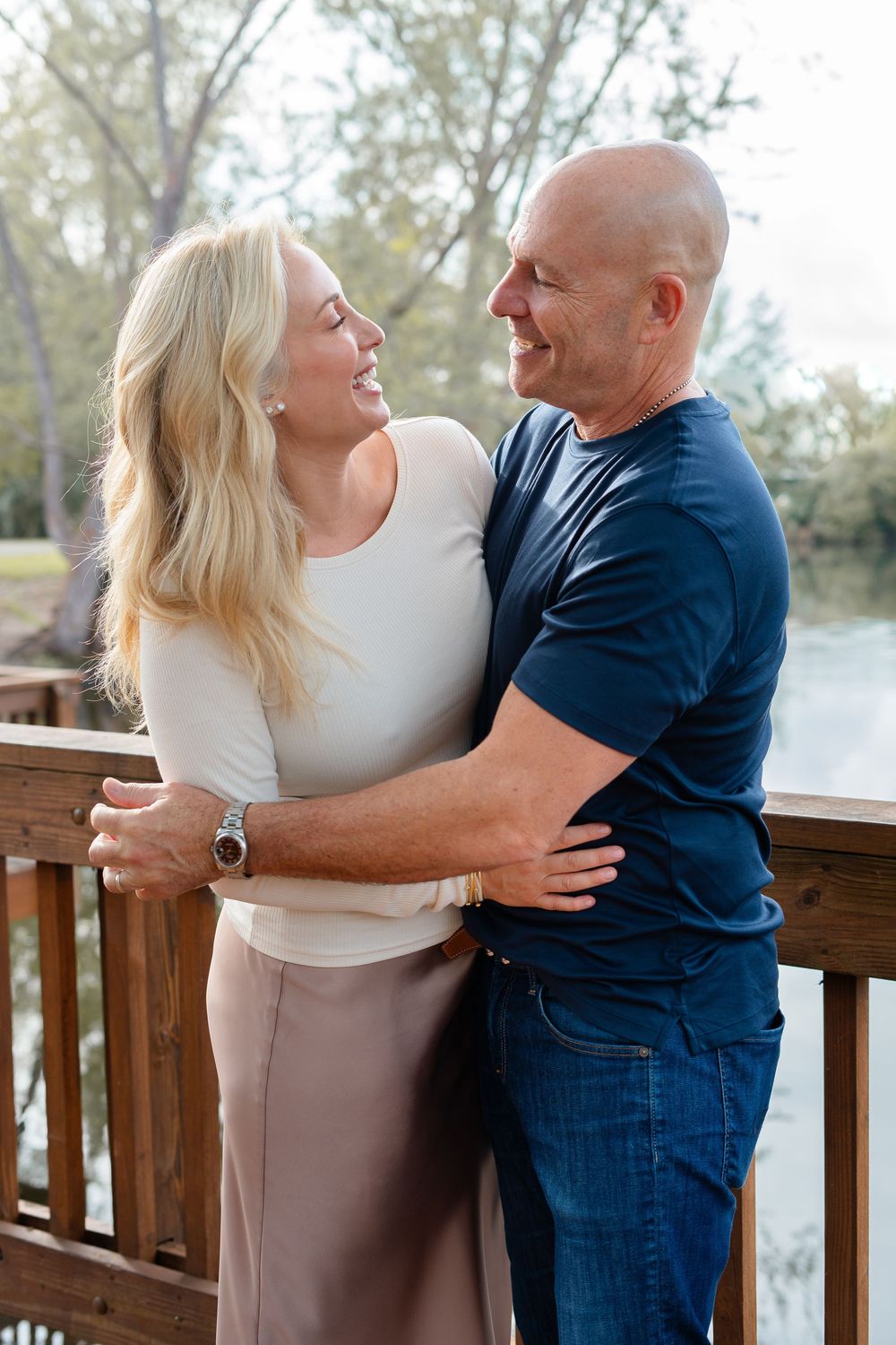 Romantic couple dancing and holding each other on a wooden deck overlooking a peaceful water view.