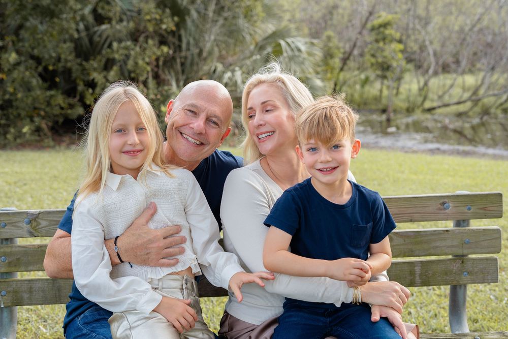 A family shares loving moments and laughter while seated together on park benches during a photo session.