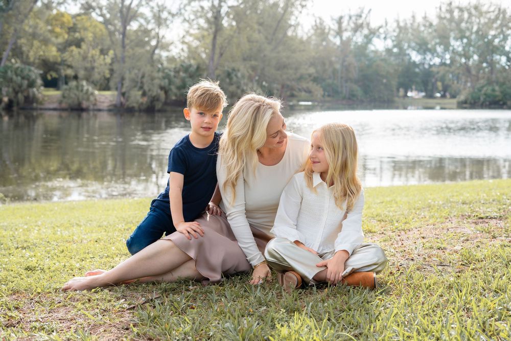 Family sits together on grass during a casual outdoor photography session in a natural setting.