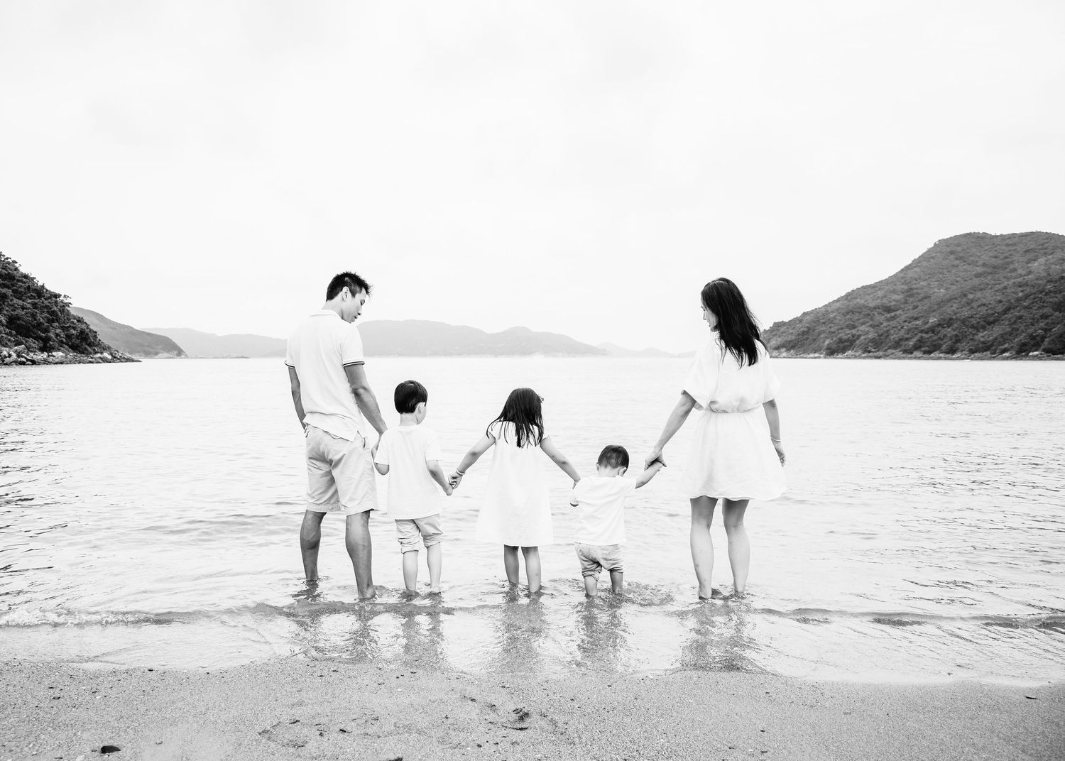 A series of black and white beach photos showing people walking along the shoreline at different angles.