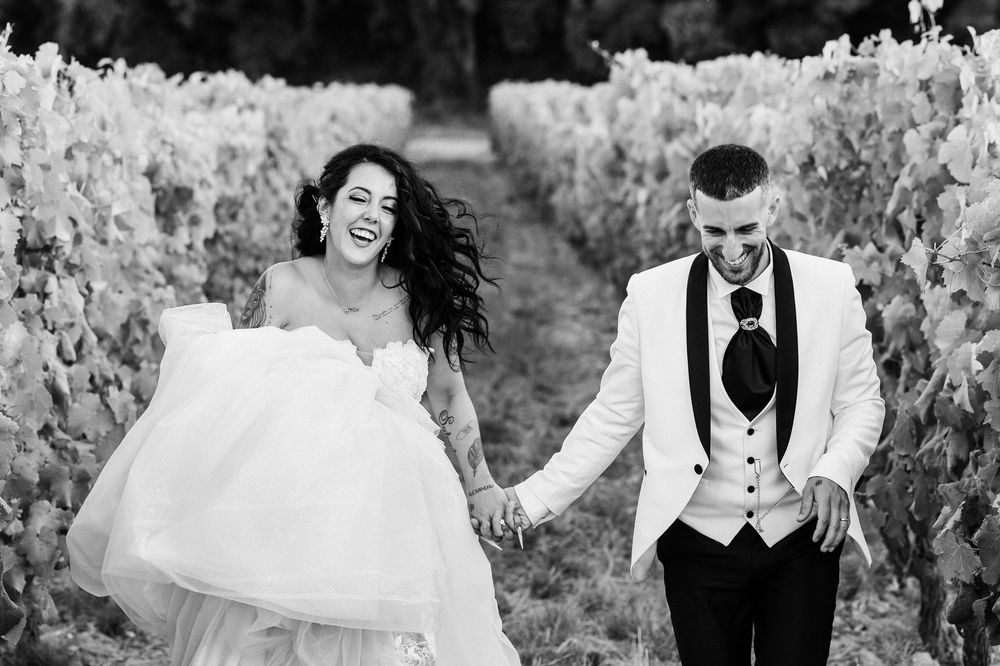 A joyful couple shares candid laughter and embraces during a black and white outdoor photo session.