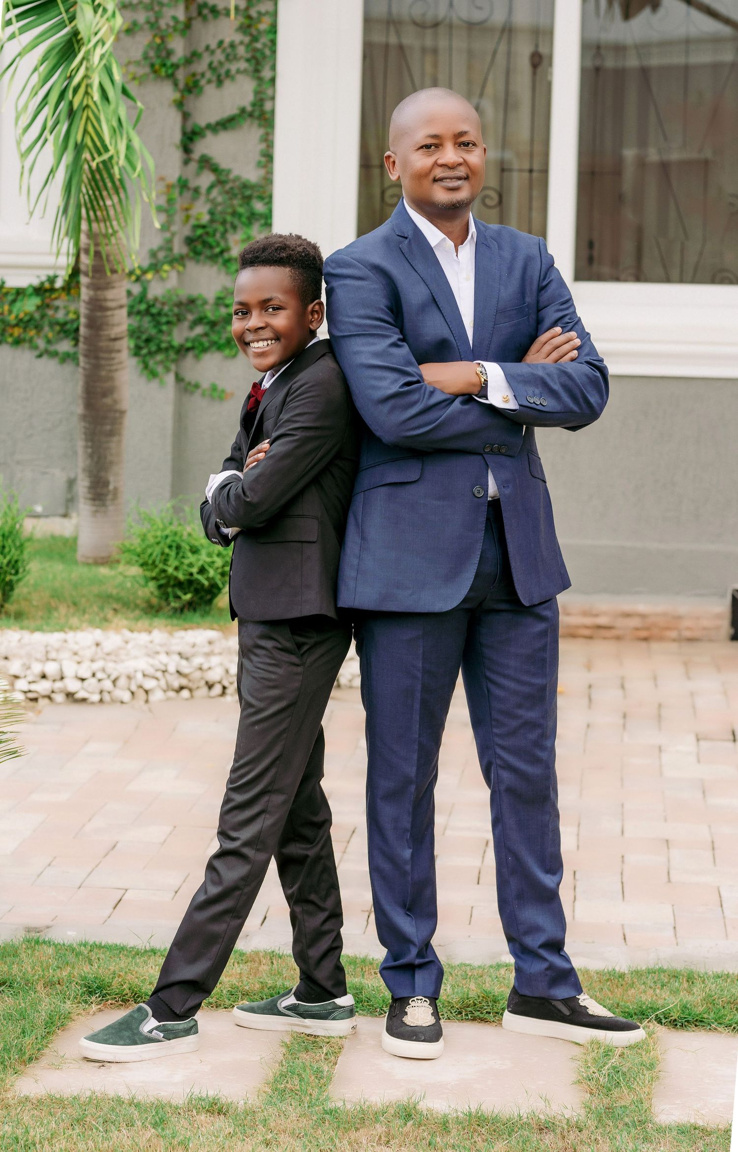 Professional portrait of two people in suits standing back-to-back outdoors.
