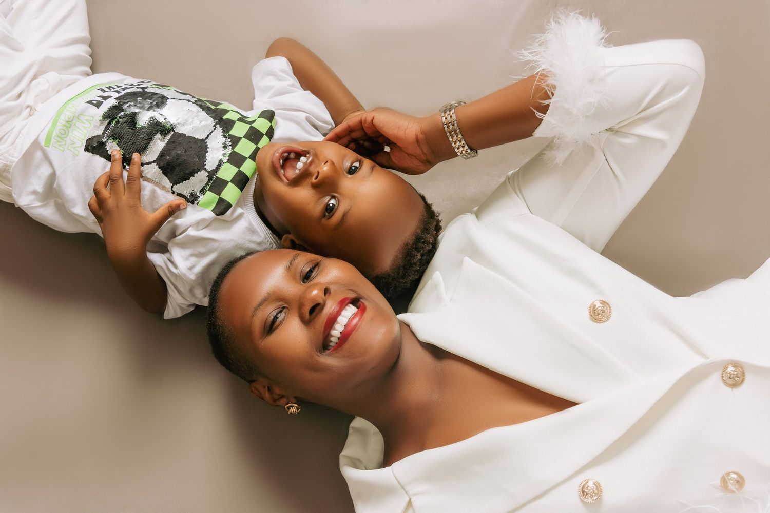 Overhead view of two people lying down wearing white outfits while laughing together.