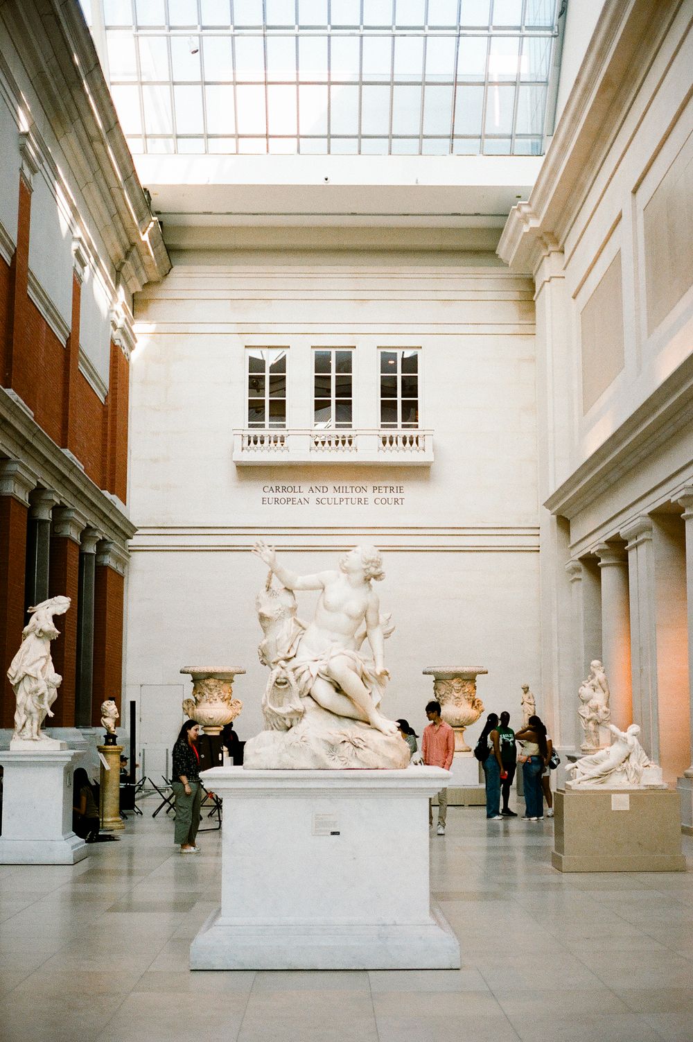 Classical marble sculptures on display in a bright museum gallery with skylight and white walls at the Metropolitan Museum of Art.