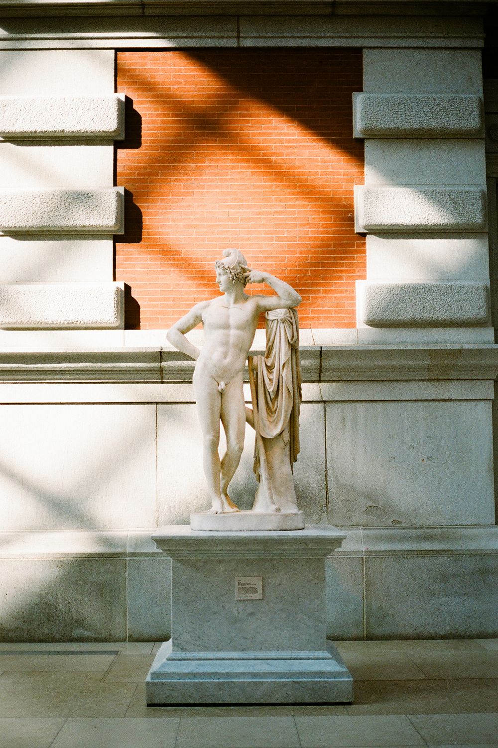 Multiple images show a modernist white stone statue on a pedestal casting dramatic diagonal shadows on a concrete wall.