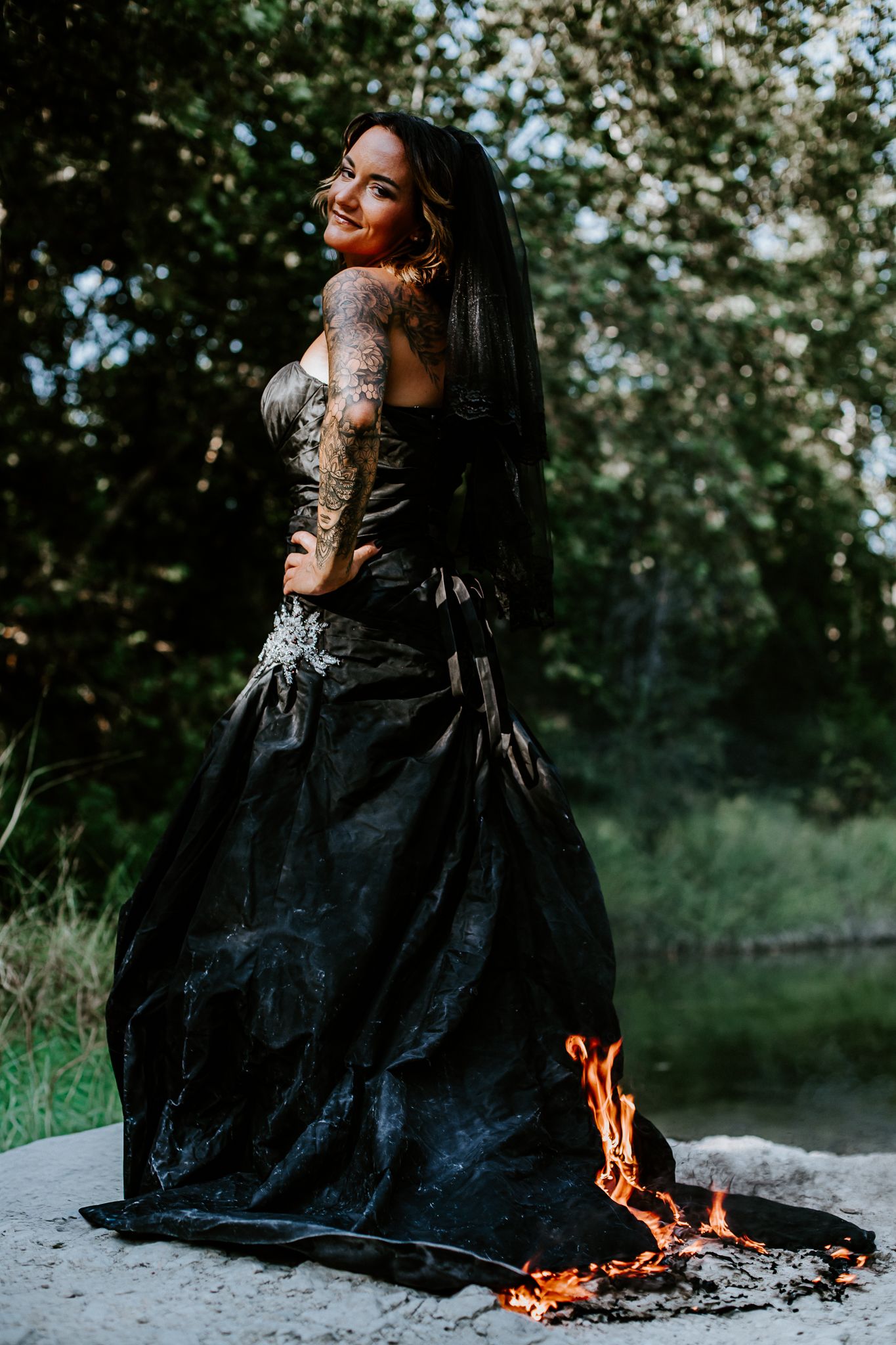 Dark formal gown with flames at the hem in dramatic outdoor setting.